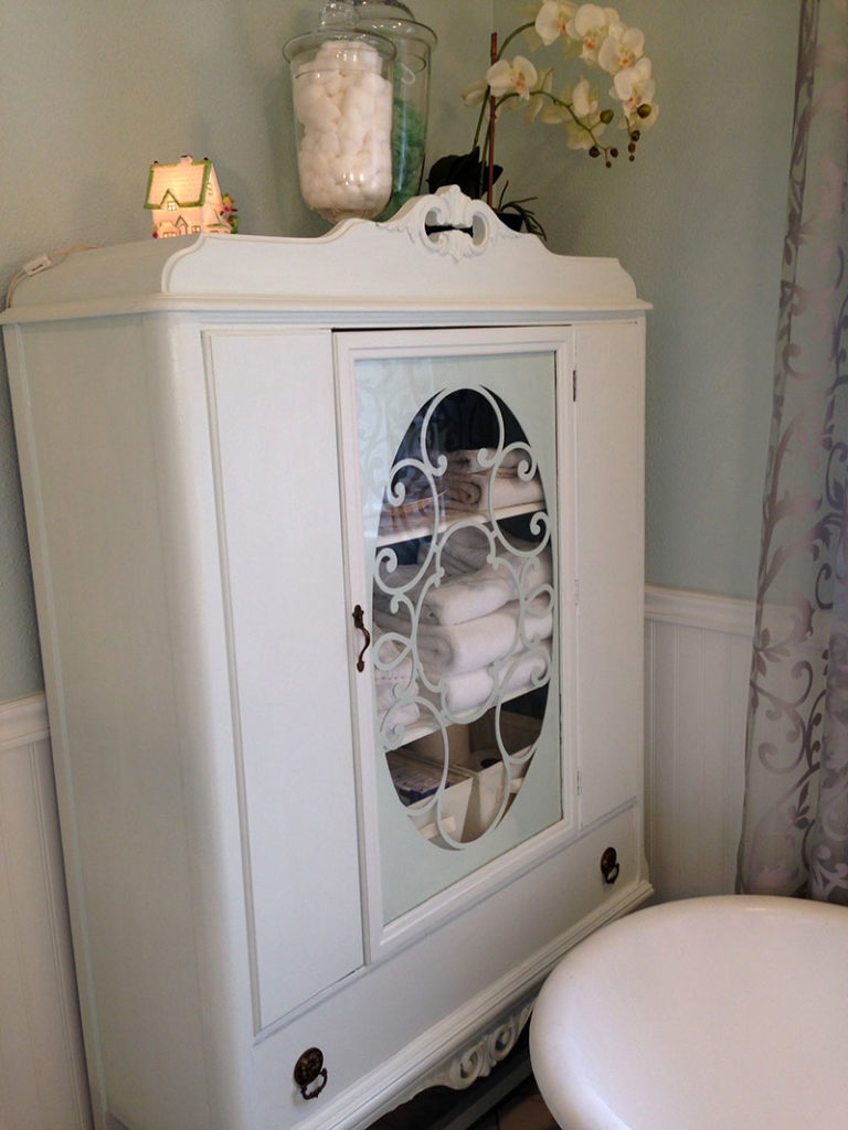 An antique china cabinet of the same era as the sideboard/vanity (and the house) now serves as bathroom storage. We went to Sacramento to get this piece, which I re-painted. See the little cottage night light I bought on Etsy?